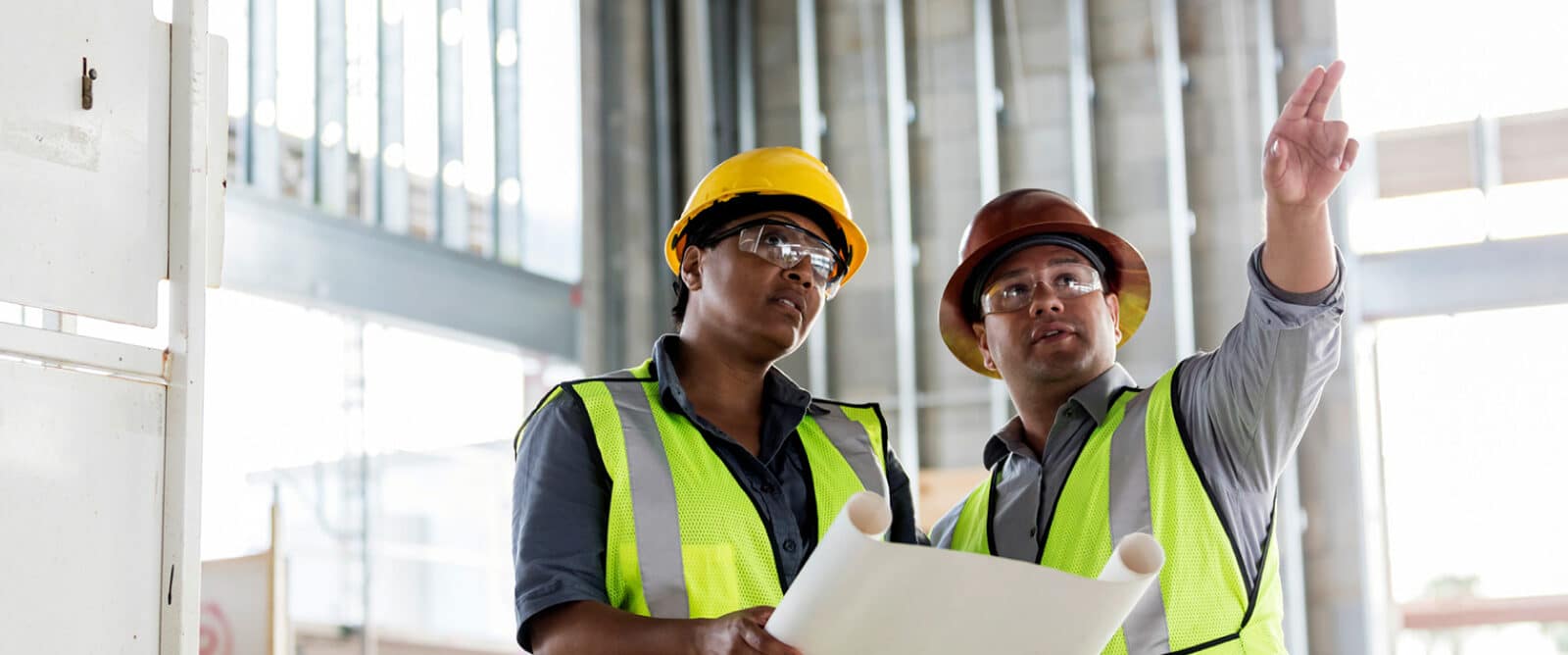 Workers holding blueprint and pointing