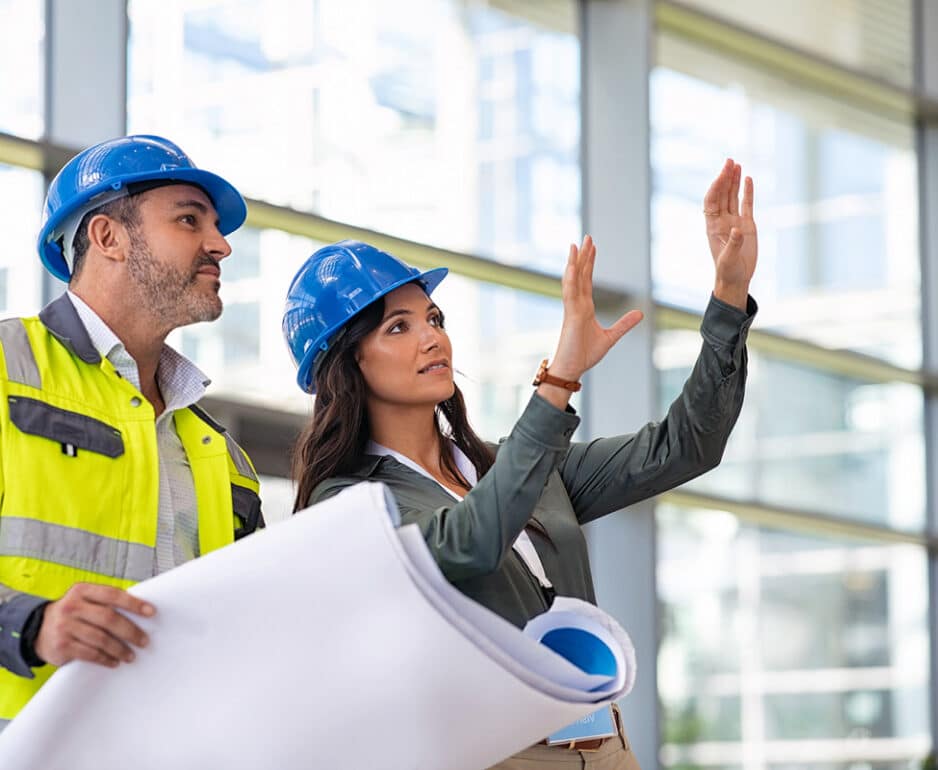 Employees wearing hard hats and holding blueprints